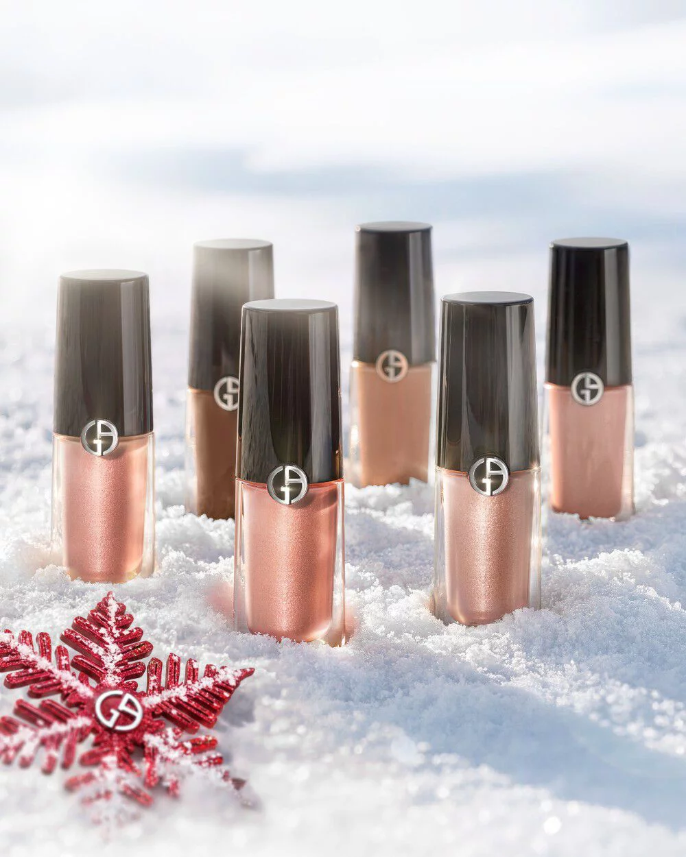 Armani beauty Eye Tint liquid eyeshadows on snow with a red holiday ornament.
