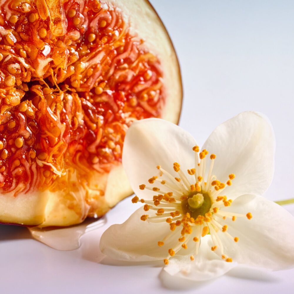 Armani Prisma Flash fragrance bottle, styled with fresh fig and white flower, illustrating the scent’s natural and sophisticated notes.