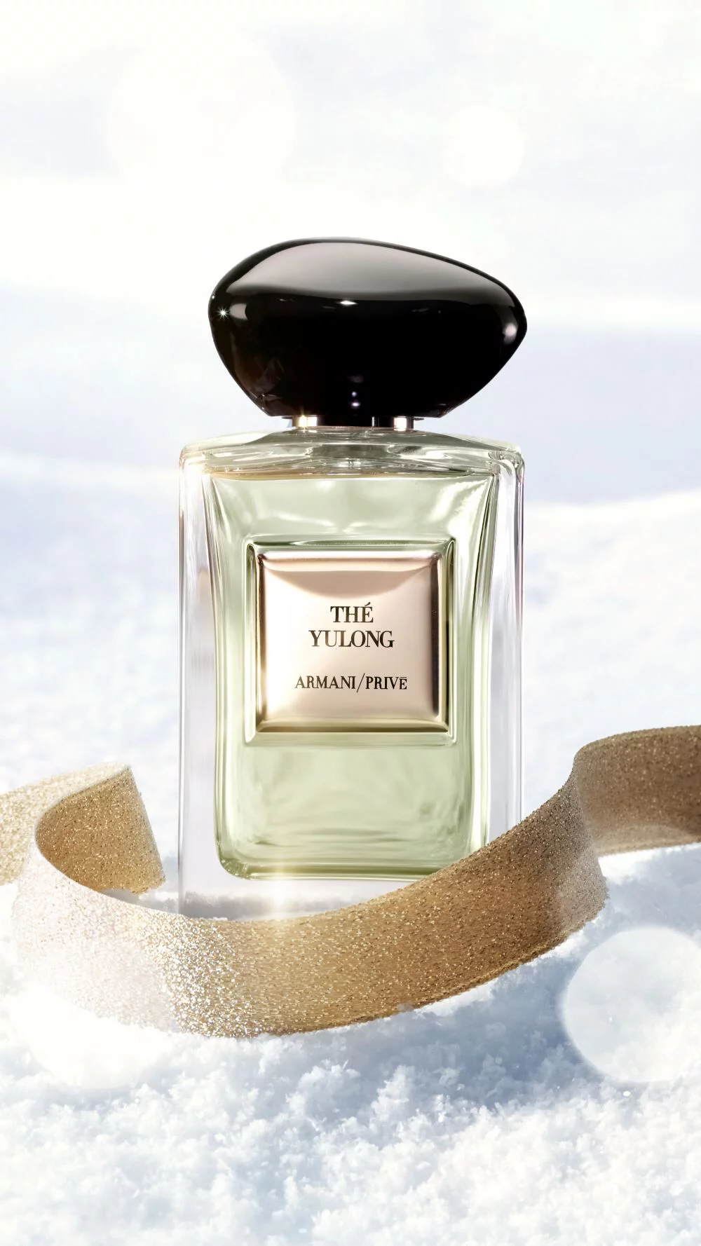 Le parfum Armani/Prive The Yulong sur la neige avec un ruban dore pour le temps des fetes.