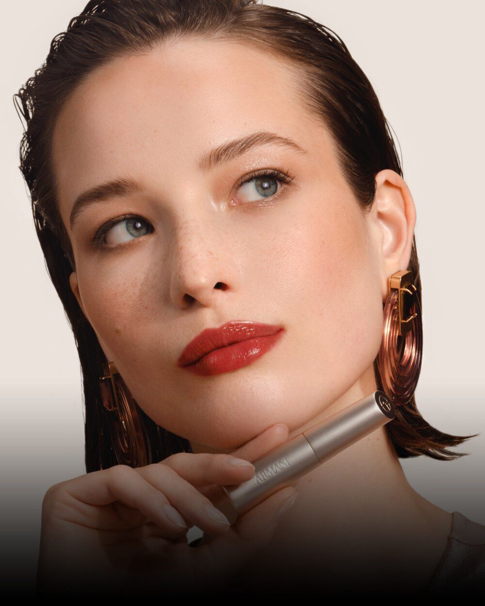 Armani Prisma Flash Scarlet Flash lipstick, showcased during application, emphasizing its bold, vibrant red pigment and sleek tube.