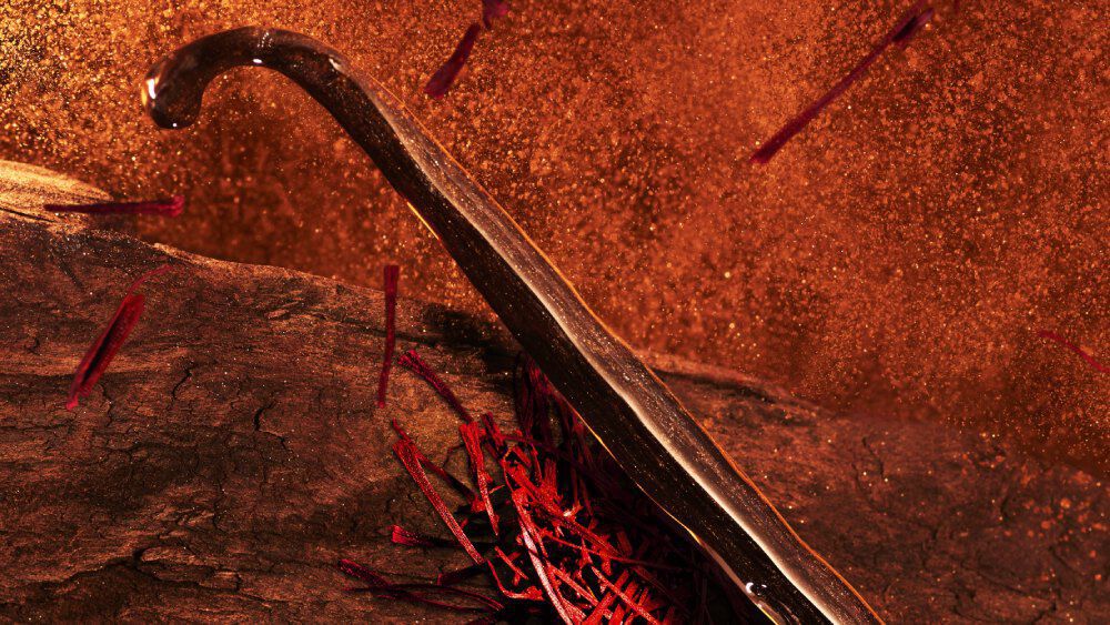 Vanilla bean and saffron displayed on a rich orange background, representing key ingredients in ARMANI STRONGER WITH YOU SPICES and emphasizing its warm, spicy signature.