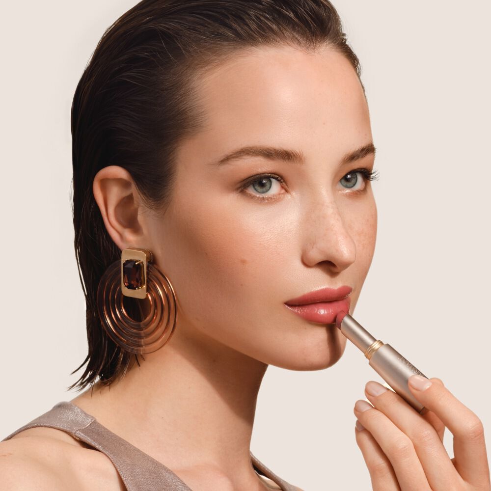 Armani Prisma Flash Scarlet Flash lipstick, showcased during application, emphasizing its bold, vibrant red pigment and sleek tube.