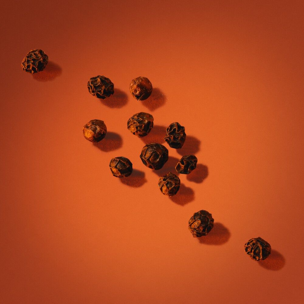 Black Pepper scattered on an orange background.