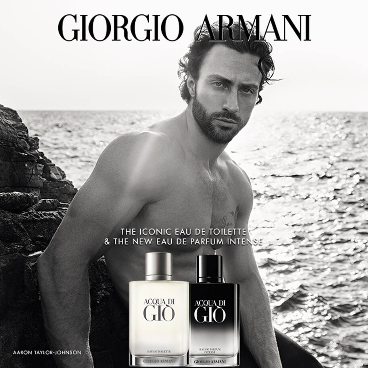 Giorgio Armani Acqua Di Gio Eau de Toilette and Eau de Parfum Intense bottles by the sea. Aaron Taylor-Johnson appears in the background.