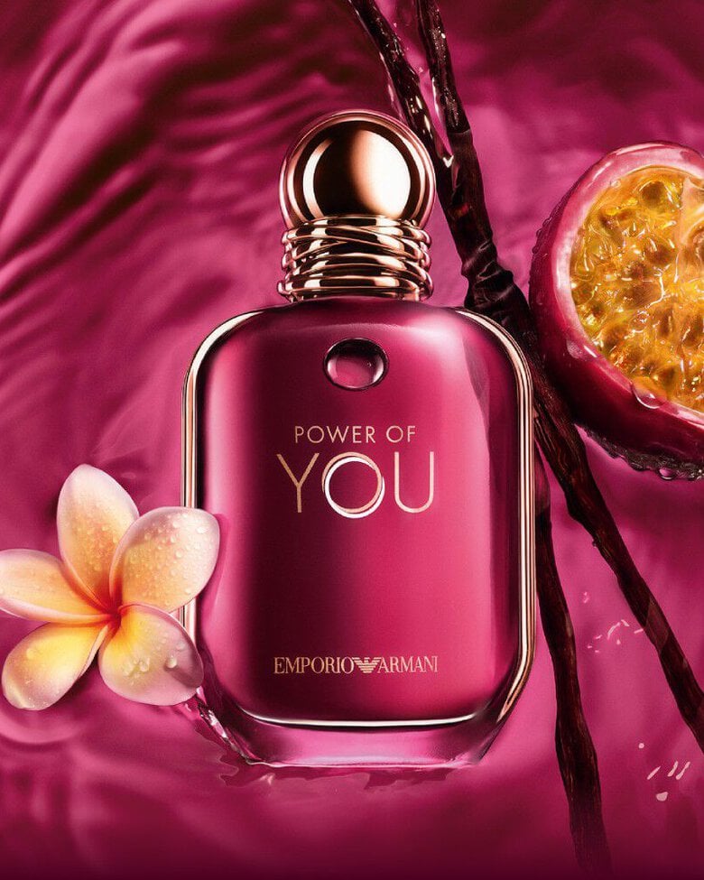 ARMANI POWER OF YOU perfume bottle surrounded by passion fruit, frangipani flowers, and vanilla beans on a radiant ruby background.