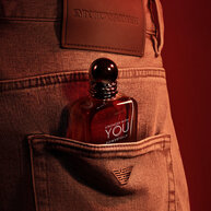 Armani fragrance bottle tucked stylishly into a denim pocket.