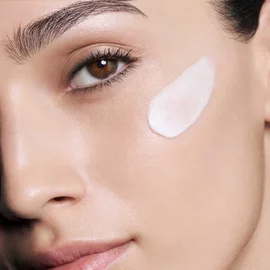 Woman's face with a dollop of CREMA NERA Sheer Cream on her cheek.