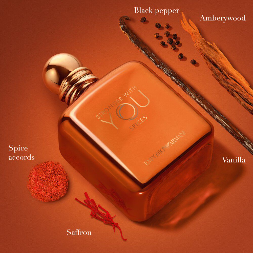 A blend of vanilla bean, saffron, spice accord, and chestnut visually arranged on an orange background, illustrating the complex, warm notes of ARMANI STRONGER WITH YOU SPICES.