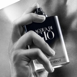 Hand holding Giorgio Armani Acqua Di Gio Eau de Parfum Intense bottle, spraying the fragrance on skin.