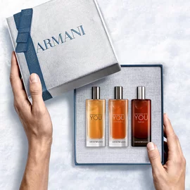 Emporio Armani Stronger With You Eau de Toilette 15ml, Stronger With You Intensely 15ml and Stronger With You Parfum 15ml — hands unveiling the three-piece fragrance gift set from within the open Armani gift box, an intimate unboxing moment.